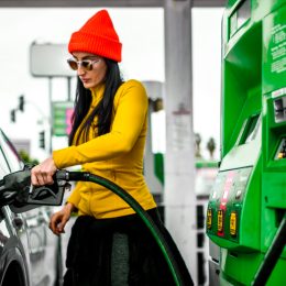 A fancy woman pouring some fuel in her car.