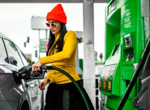 A fancy woman pouring some fuel in her car.
