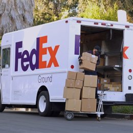 FedEx driver loading boxes into delivery truck day exterior