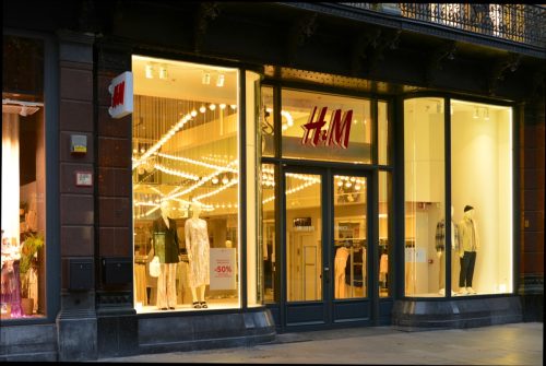 H&M shop in the early morning, doors are still closed. Interior window display are still illuminating the dark.