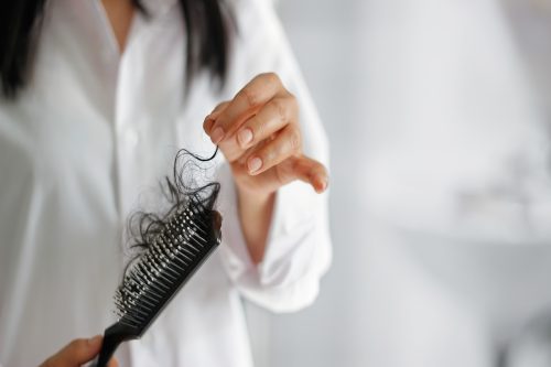 woman losing hair on hairbrush