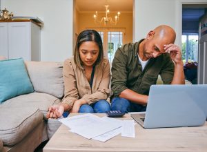 Shot of a young couple reviewing their finances while using their laptop and being stressed