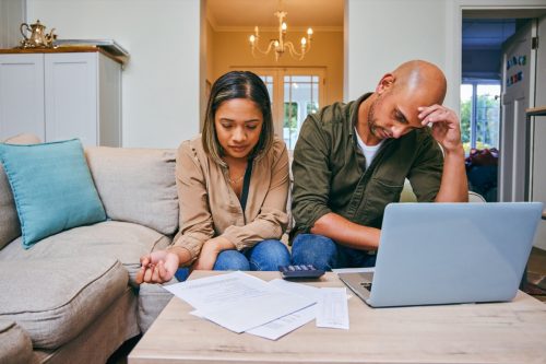 Shot of a young couple reviewing their finances while using their laptop and being stressed