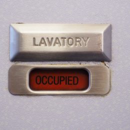 A lavatory sign on a plane bathroom door that says "occupied"