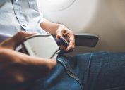 A man buckling his seatbelt on a plane