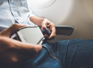 A man buckling his seatbelt on a plane