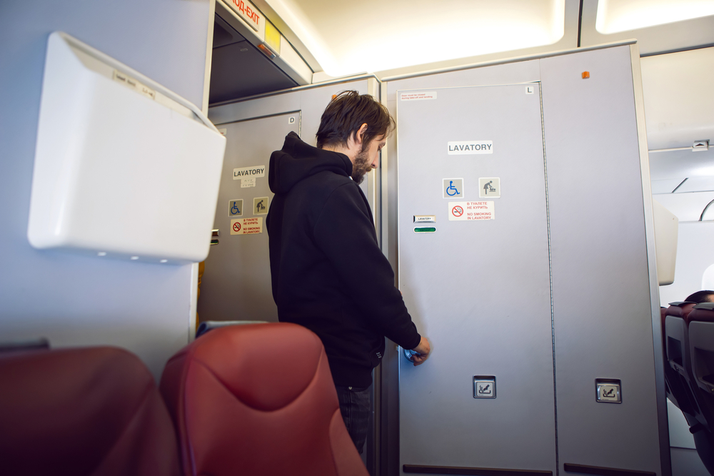 A man entering a plane bathroom or lavatory during a flight