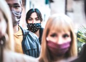 commuter crowd of people moving on city street covered by face mask - New normal human condition and society concept - Focus on middle woman wearing black facemask - Desaturated contrast filter