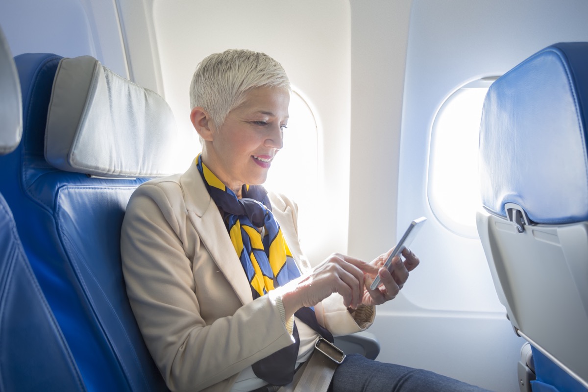 O femeie de afaceri care folosește un smartphone în avion