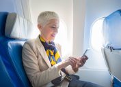 Business woman using smart phone at plane