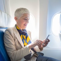 Business woman using smart phone at plane