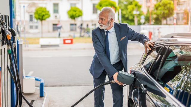 Senior man refueling his car the gas station.