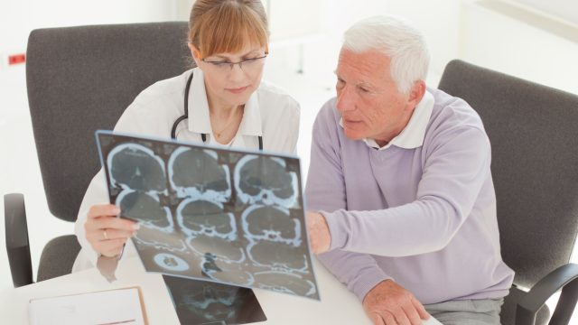 A senior man visiting with his doctor and looking at a CT scan of his brain