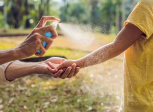 Spraying insect repellent on skin outdoors
