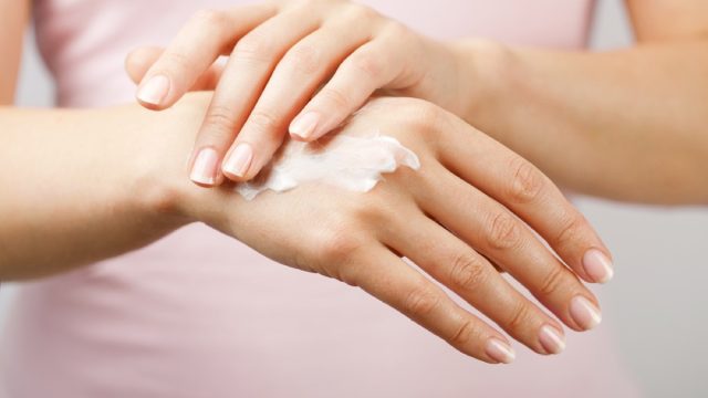 close up of woman applying moisturizer to back of hand