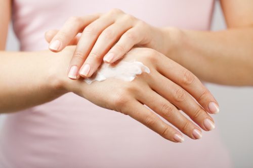 close up of woman applying moisturizer to back of hand
