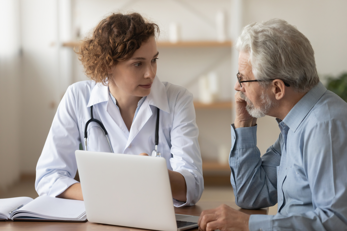 Młody profesjonalny lekarz lekarz konsultacji starego pacjenta płci męskiej, rozmawiając z starszym klientem dorosłym mężczyzną podczas wizyty kontrolnej.