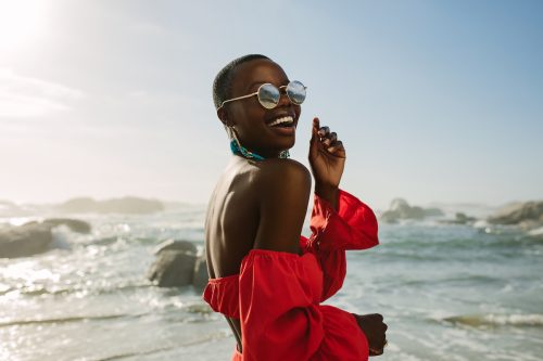 femeie zâmbind în fața oceanului