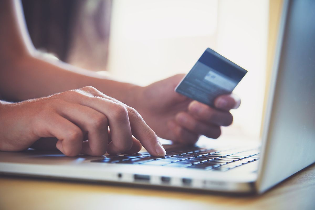 Hand holding credit card and using laptop