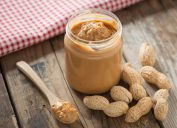 Creamy and smooth peanut butter in jar on wood table