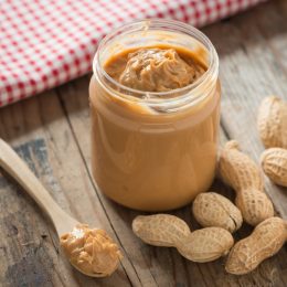 Creamy and smooth peanut butter in jar on wood table