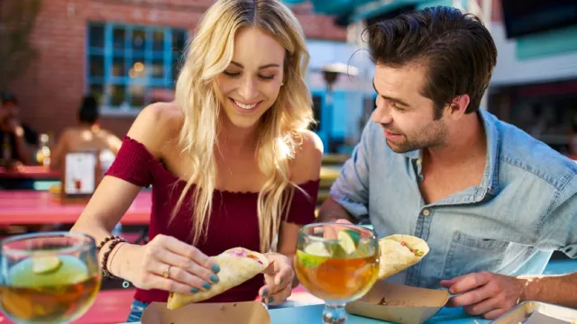 couple sharing tacos at an outdoor restaurant