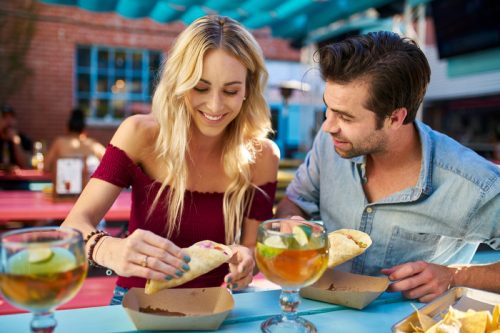 Cuplu care împarte tacos la restaurantul în aer liber