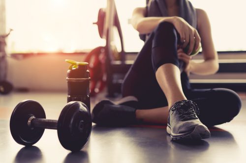 Người phụ nữ tập thể dục trong phòng tập thể dục đang nghỉ ngơi đang cầm quả táo sau khi tập luyện thể thao với quả tạ và chai lắc protein lối sống lành mạnh thể hình