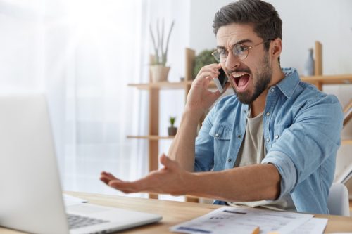 man yelling at computer and gesticulating wildly