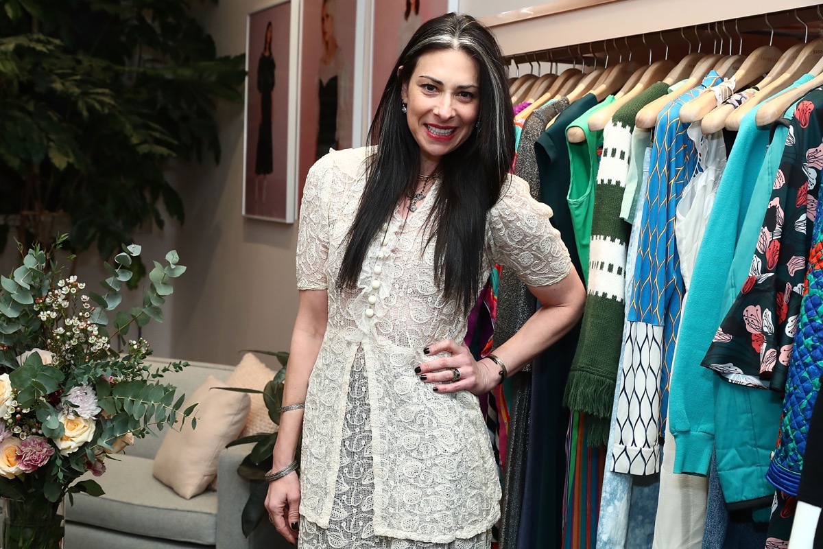 stacy london standing in front of a rack of clothes