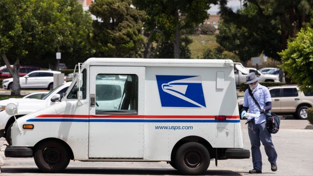 A USPS (United States Parcel Service) mail truck and postal carrier make a delivery.