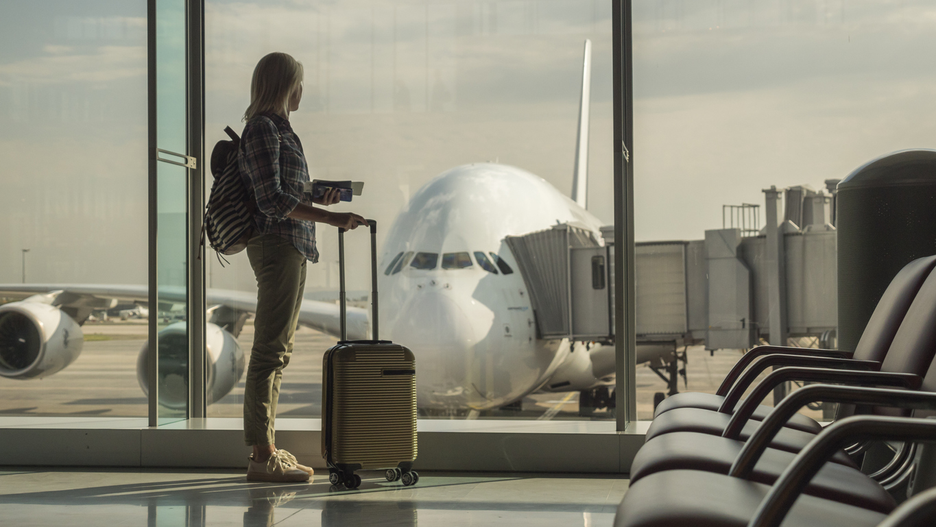 A woman standing with her suitcase in the airport about to board a flight