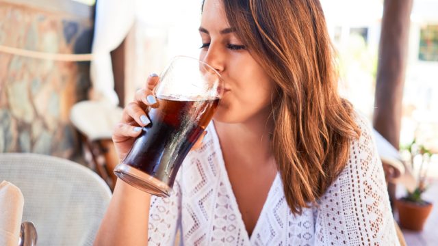A young woman drinking diet soda outdoors