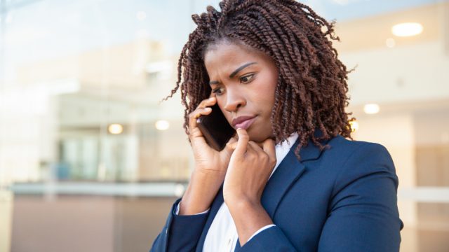A young woman taking a phone call with a concerned look on her face