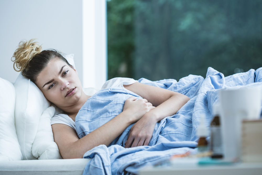 Tânără întinsă pe canapea și pătură cu simptome de coronavirus, răceală sau gripă