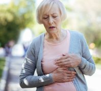 A senior woman walking and holding her chest with heart attack symptoms