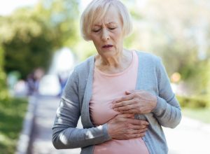 A senior woman walking and holding her chest with heart attack symptoms
