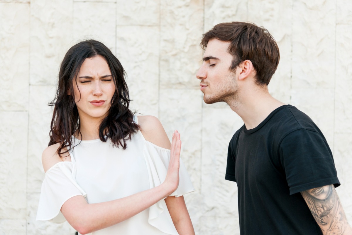 man trying to kiss woman who doesn't want to kiss