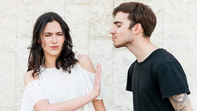 man trying to kiss woman who doesn't want to kiss