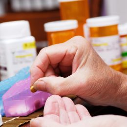 Senior woman taking meds from pill organizer