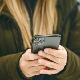 The girl uses a new cell phone with a triple camera.