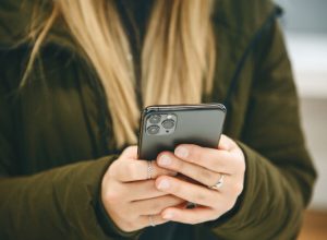 The girl uses a new cell phone with a triple camera.