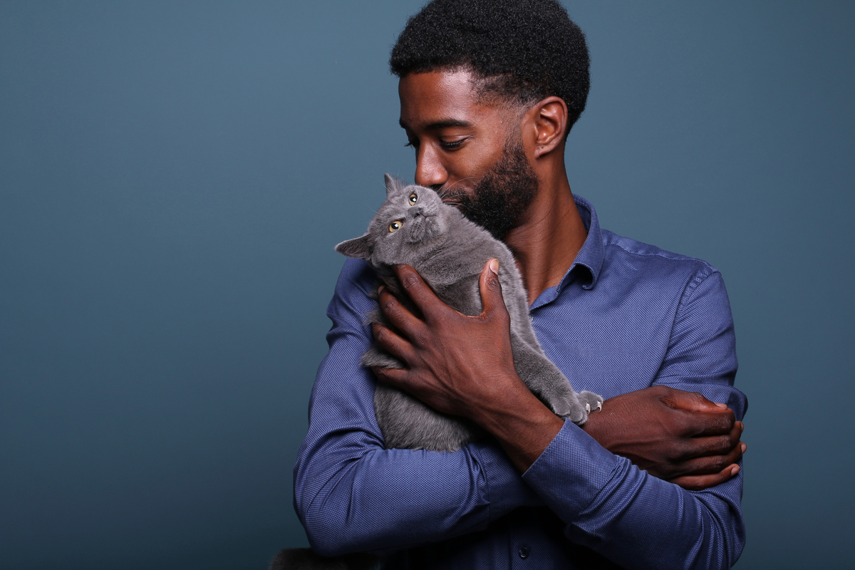 young black man holding gray cat