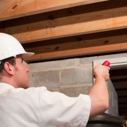An exterminator or pest control agent looking at eaves in the ceiling of a basement or attic