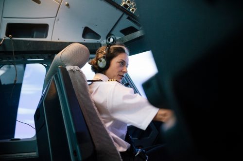 A flight instructor sitting in the cockpit of a simulator is operating an aircraft during a training session.