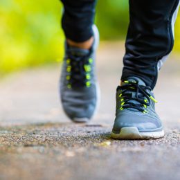Closeup of a man's sneakers while he walks outside on a paved path