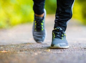 Closeup of a man's sneakers while he walks outside on a paved path