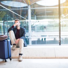 A man sitting in an airport with a distressed look on his face due to a delayed or cancelled flight