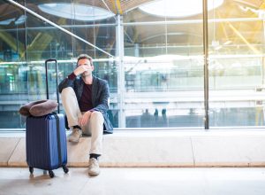 A man sitting in an airport with a distressed look on his face due to a delayed or cancelled flight
