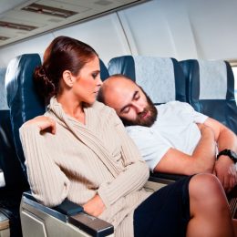 man sleeping on woman's shoulder on airplane